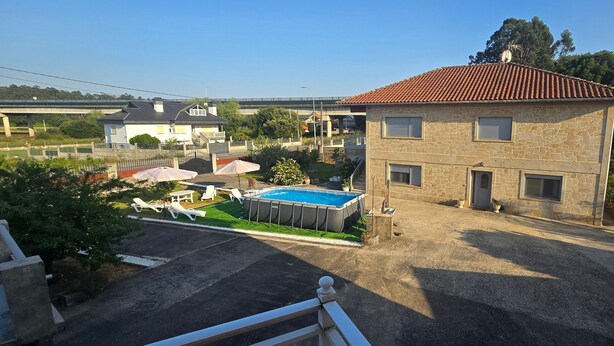 Ein zweistöckiges Steinhaus mit Swimmingpool, Außenbereich zum Sitzen und Blick auf eine Brücke im Hintergrund.