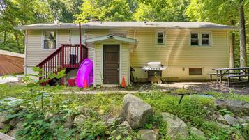 A single-story house with a front porch, a small attached garage, and a picnic table.