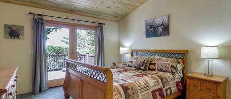 A bedroom with a wooden bed, a nightstand with a lamp, a dresser, a balcony door, and a ceiling fan.