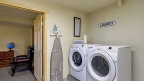 Ein Waschraum mit zwei Waschmaschinen mit Frontlader, einem Holzstuhl, einem Globus und einem gerahmten Schild an der Wand.