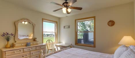 A bedroom with a bed, dresser, chair, desk, and windows.