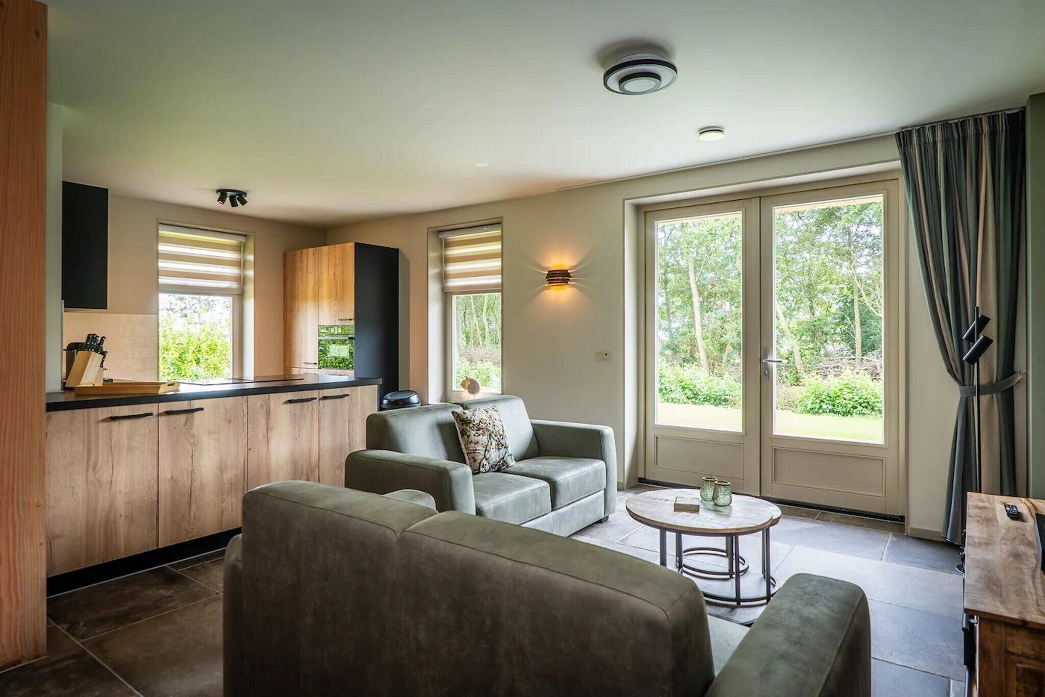 A modern living space with a kitchen, seating area, and large windows.