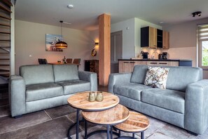 A modern living room with two grey sofas, a wooden coffee table, and a dining area with a painting. - Farmhouse near De Koog (De Koog)