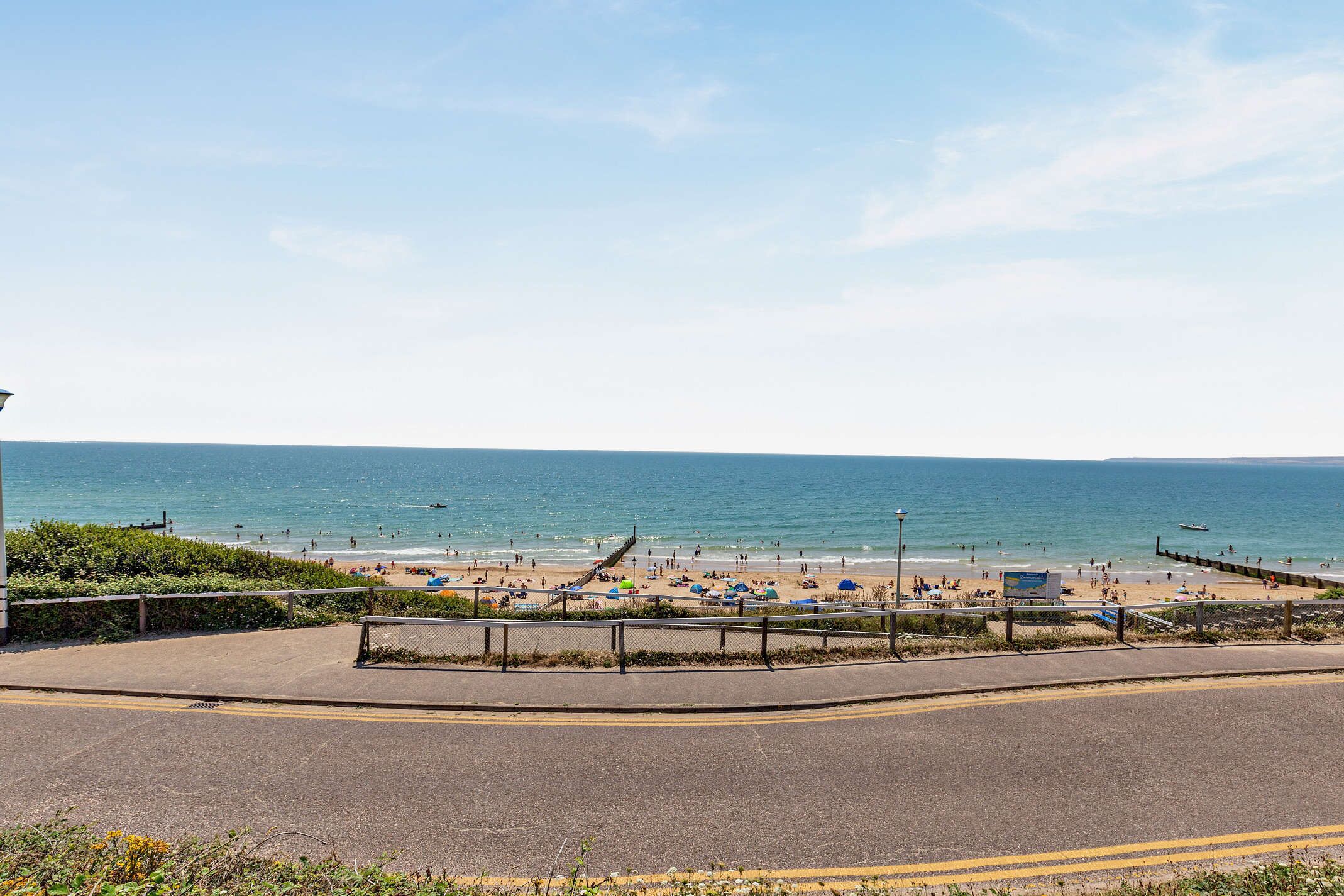 Uma estrada costeira que leva a uma praia, com vista clara para o mar.