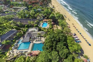 Luftaufnahme eines Resorts mit Schwimmbad, Strand und Meer.