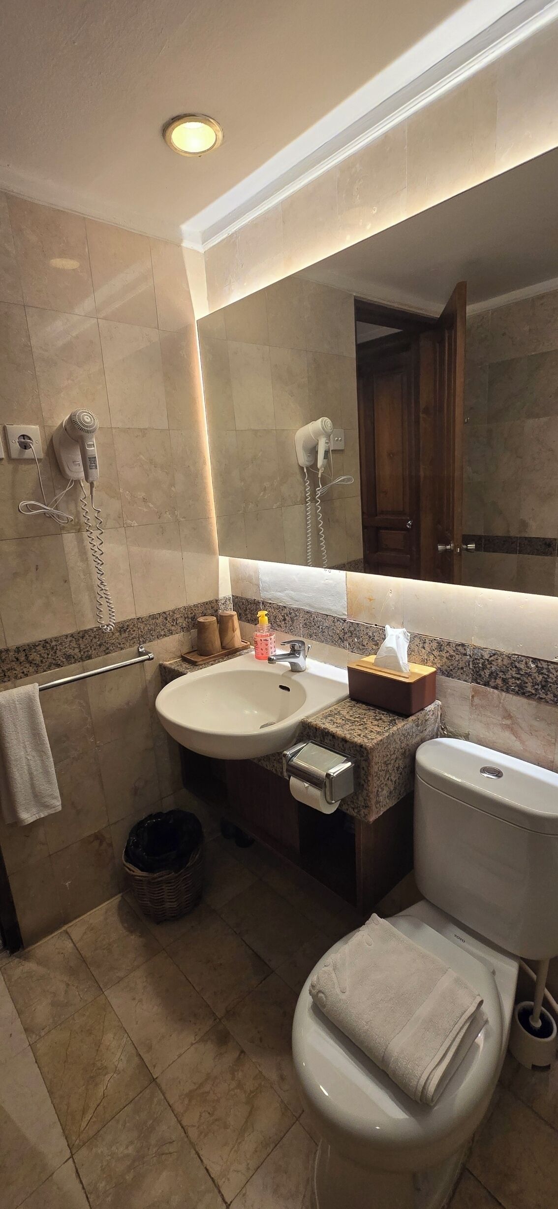Ein Badezimmer mit Waschbecken, Spiegel, Toilette und Föhn.