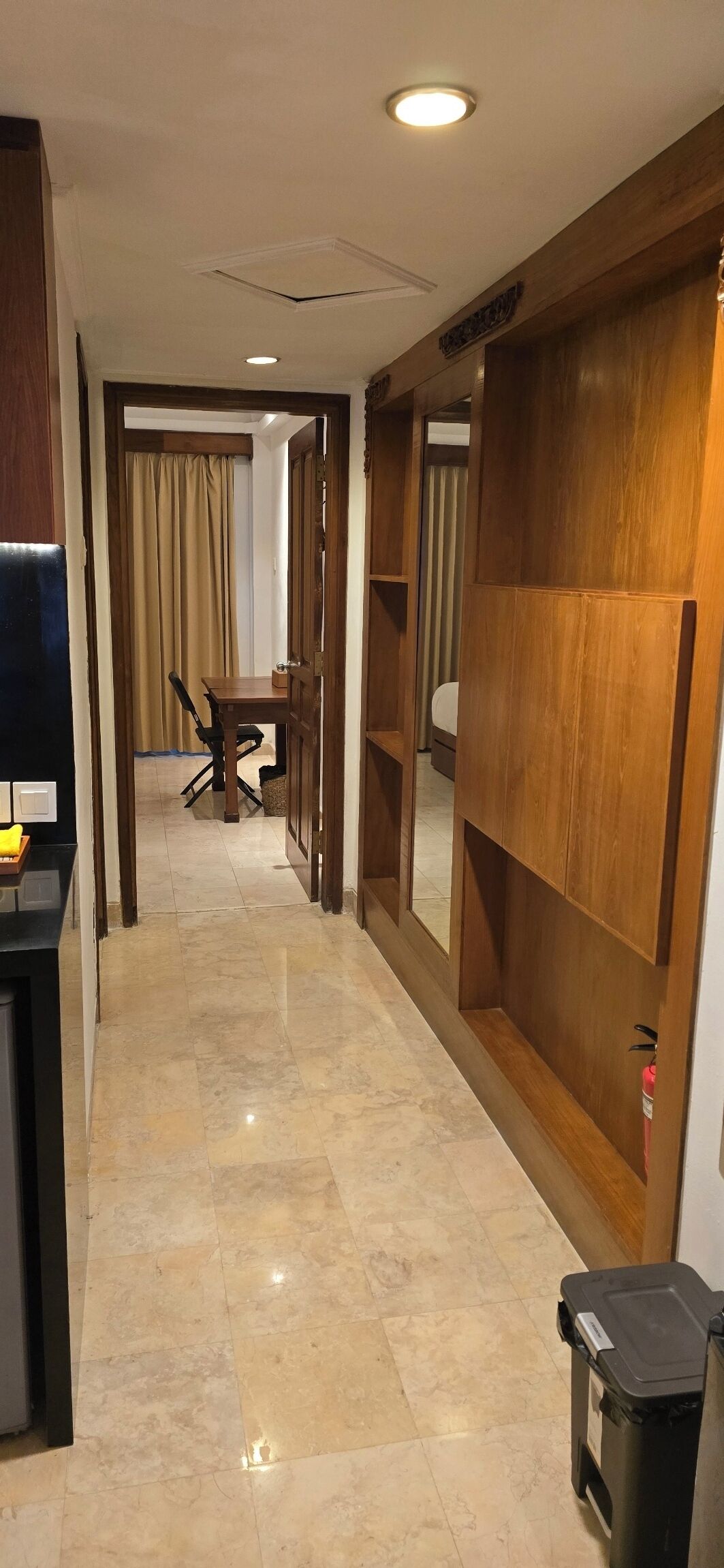 A hotel corridor with a dining area, wooden paneling, and a trash bin.