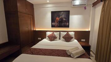 A hotel room with a bed, a headboard with a picture, a wardrobe, and a nightstand.