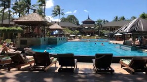 A resort pool area with lounge chairs, a central pool, and a building with a dome roof.