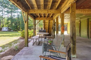 Un espacio al aire libre techado con una mesa, sillas y una parrilla.