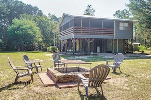 A two-story cabin with a deck, outdoor seating area, and a fire pit.