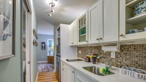 A kitchen with white cabinets, a coffee bar, and a tiled backsplash. - 1 BR Ocean Inlet View with Private Pool (Murrells Inlet)