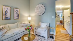 A living room with a sofa, armchair, coffee table, and wall art. - 1 BR Ocean Inlet View with Private Pool (Murrells Inlet)