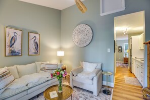 Ein Wohnzimmer mit Sofa, Sessel, Couchtisch und Wandbildern.
