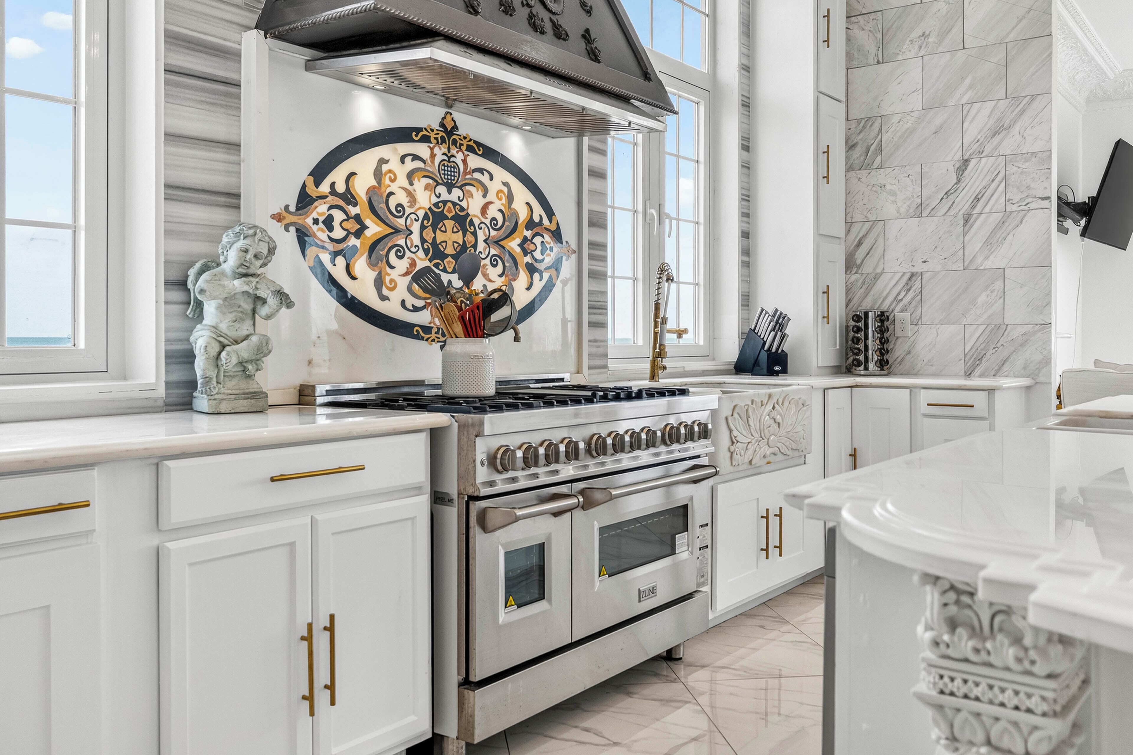 A modern kitchen with white cabinetry, a large stove, and decorative tiles.
