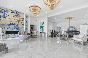 A luxurious living room with marble flooring, ornate furniture, and a large wall mural. - Oceanfront DeBordieu Estate, Direct Beach Access (Georgetown)