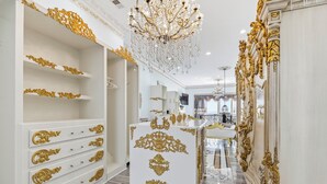 Ein luxuriöses Interieur mit aufwendigen Goldverzierungen, einer prunkvollen Chandelier und einem gut beleuchteten Flur, der zu einem Badezimmer führt.