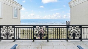 Ein Balkon mit Meerblick, ein Geländer mit Zierleisten und ein Gebäude mit einem Fenster.