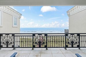Ein Balkon mit Meerblick, ein Geländer mit Zierleisten und ein Gebäude mit einem Fenster.