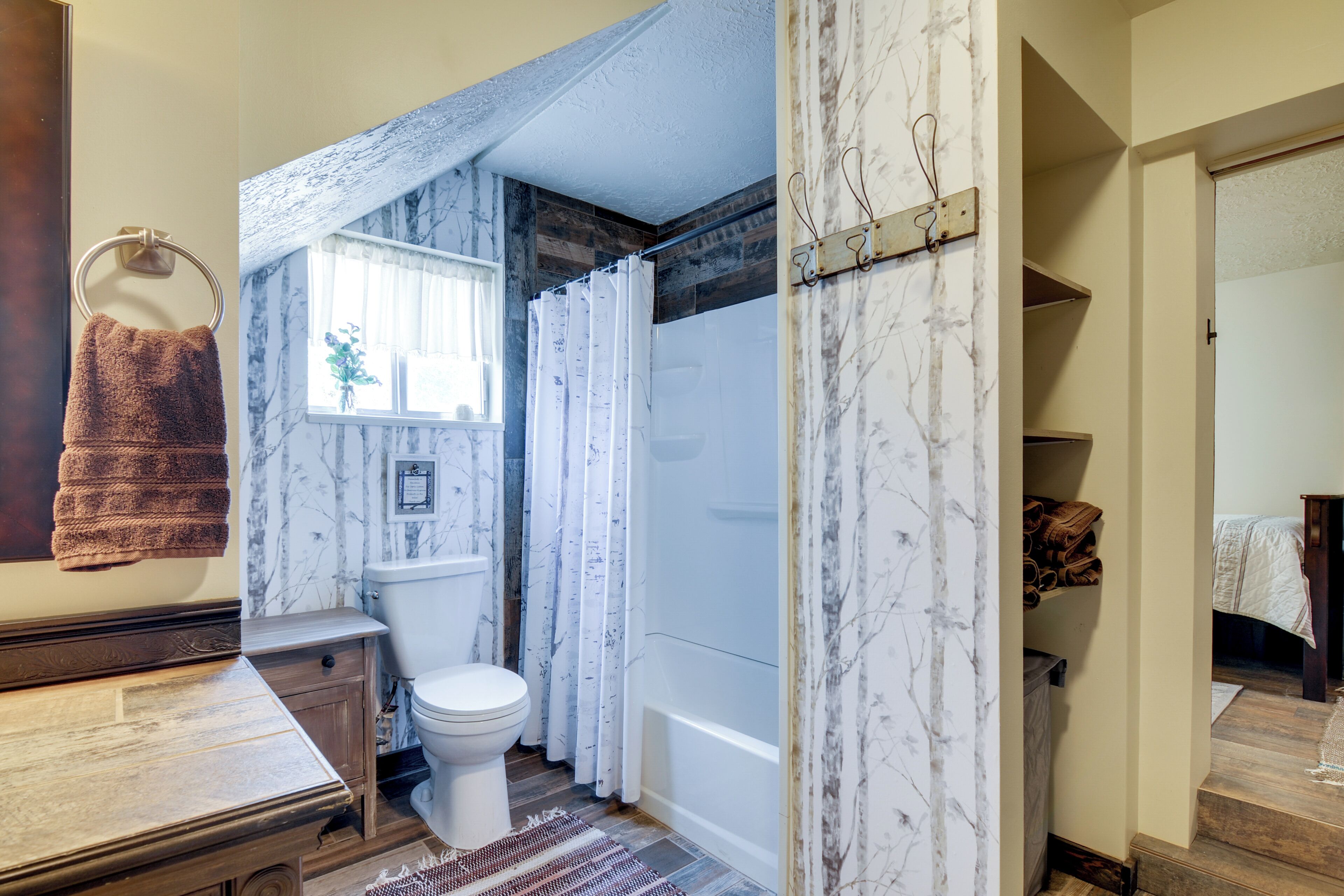 Een badkamer met toilet, douche en een houten wastafelmeubel.