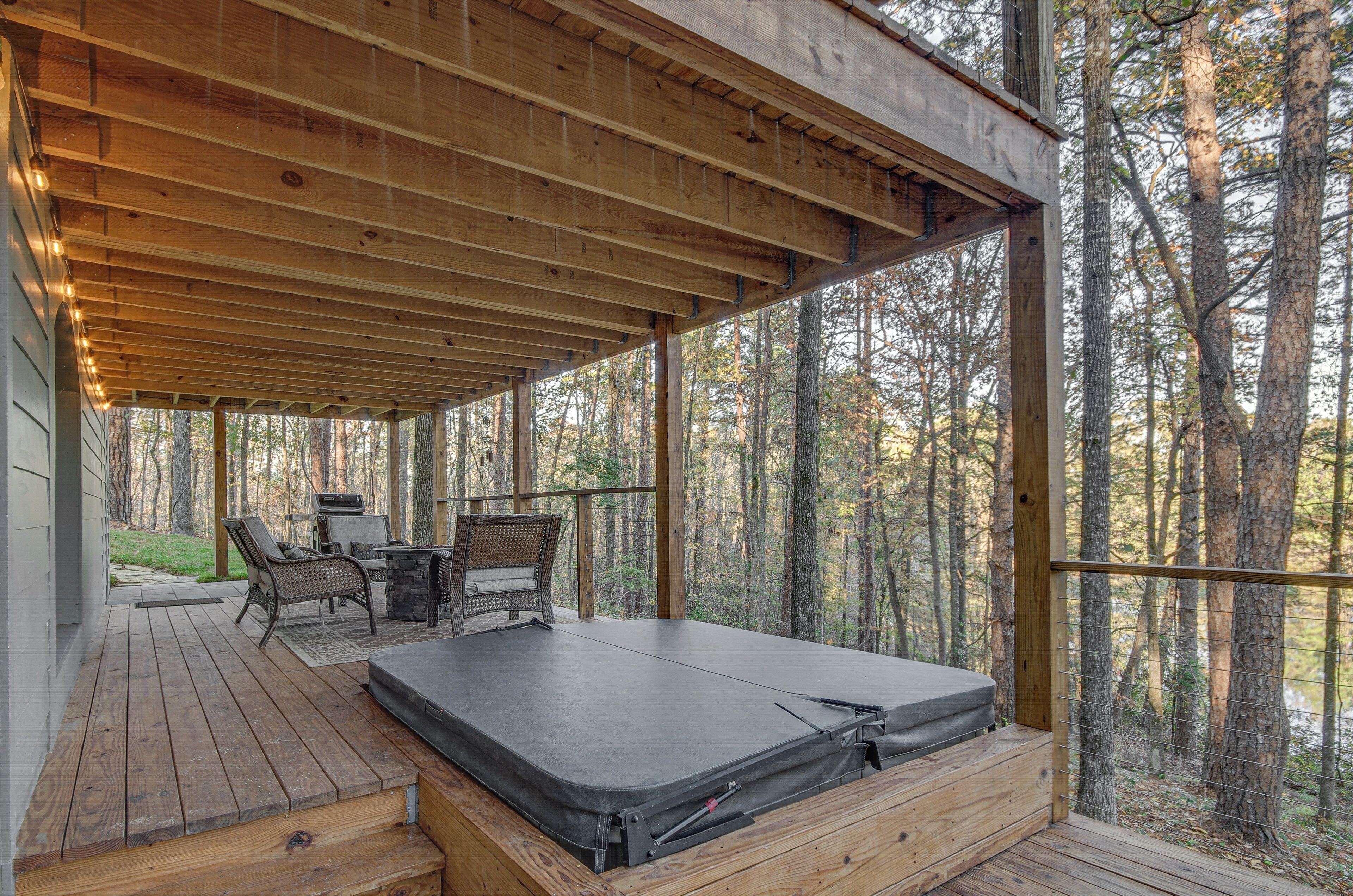 Une terrasse extérieure couverte, dotée d’un plafond en bois, d’un matelas et d’une table avec des chaises.