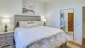 A bedroom with a large bed, two bedside tables with lamps, a wooden door, and a mirror.