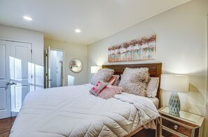 Ein Schlafzimmer mit einem großen Bett, einem Nachttisch mit Lampe, einem Spiegel und einem Bild an der Wand.