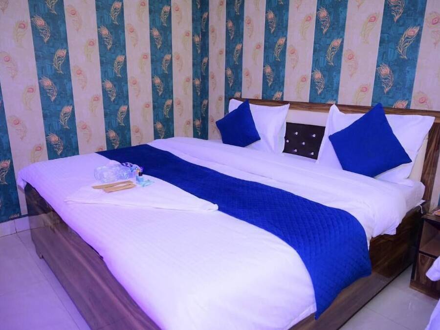 A double bed with a blue and white bedspread, two pillows, and a wooden headboard.