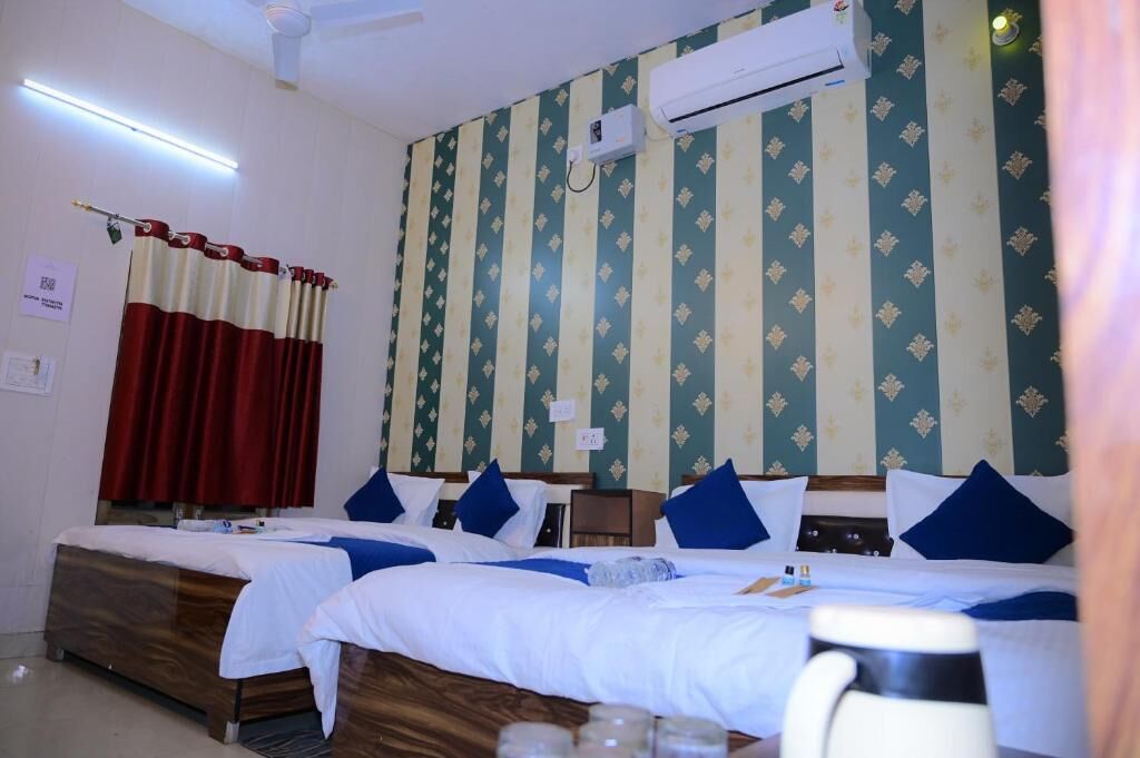 A hotel room with two beds, a ceiling fan, an air conditioning unit, and striped wallpaper.