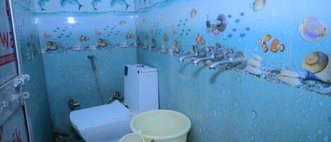A bathroom with a blue wall, a toilet, a sink, and a shower. There are decorative fish and seashells on the wall.