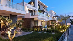 Un moderno edificio residenziale a più piani con balconi, area salotto esterna e curato giardino.