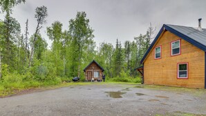 En stuga med en grusuppfart och en skog som bakgrund.