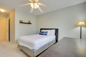 A bedroom with a bed, a ceiling fan, a nightstand, a lamp, and decorative wall art. - Charleston Townhome Near Credit One Stadium (Charleston)