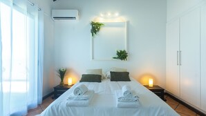 A hotel room with a bed, bedside lamps, a mirror, and a potted plant. - Costa Bela Retreat Azores: The perfect getaway, offering comfort, nature, and serenity. (Açores)