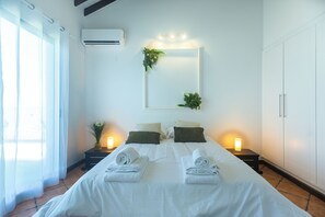 A hotel room with a bed, bedside lamps, a mirror, and a potted plant. - Costa Bela Retreat Azores: The perfect getaway, offering comfort, nature, and serenity. (Açores)
