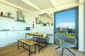 A modern kitchen with white cabinets, a wooden dining table, and a grey chair. - Costa Bela Retreat Azores: The perfect getaway, offering comfort, nature, and serenity. (Açores)