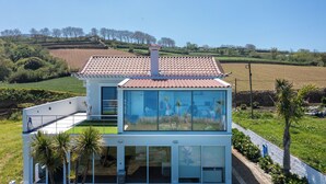 A modern house with a tiled roof, large glass windows, and a green roof. - Costa Bela Retreat Azores: The perfect getaway, offering comfort, nature, and serenity. (Açores)