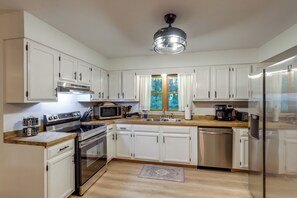 A kitchen with white cabinets, stainless steel appliances, a wooden countertop, and a window with curtains. - Mins from AVL, Woodsy Weaverville Retreat (Weaverville)