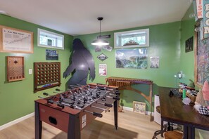 A room with green walls, a foosball table, a window, and various wall decorations. - Mins from AVL, Woodsy Weaverville Retreat (Weaverville)