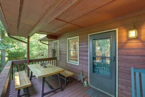A wooden deck with a table and benches, a door with a window, and a wall-mounted light fixture. - Mins from AVL, Woodsy Weaverville Retreat (Weaverville)