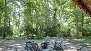 An outdoor seating area with Adirondack chairs and a fire pit, surrounded by a wooded environment. - Mins from AVL, Woodsy Weaverville Retreat (Weaverville)