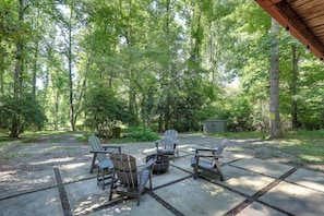 An outdoor seating area with Adirondack chairs and a fire pit, surrounded by a wooded environment. - Mins from AVL, Woodsy Weaverville Retreat (Weaverville)