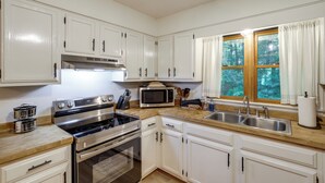 A kitchen with white cabinets, stainless steel appliances, and a window with curtains. - Mins from AVL, Woodsy Weaverville Retreat (Weaverville)