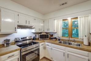 A kitchen with white cabinets, stainless steel appliances, and a window with curtains. - Mins from AVL, Woodsy Weaverville Retreat (Weaverville)