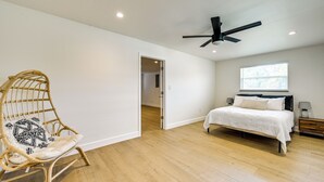 A bedroom with a bed, a wicker chair, a ceiling fan, and a window. - Modern 2-Unit Combo w/ Pool: 'Naples Hideaway' (Naples)