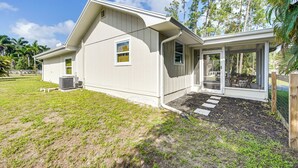 A single-story house with a covered porch, a small patio, and a yard with grass and mulch. - Modern 2-Unit Combo w/ Pool: 'Naples Hideaway' (Naples)