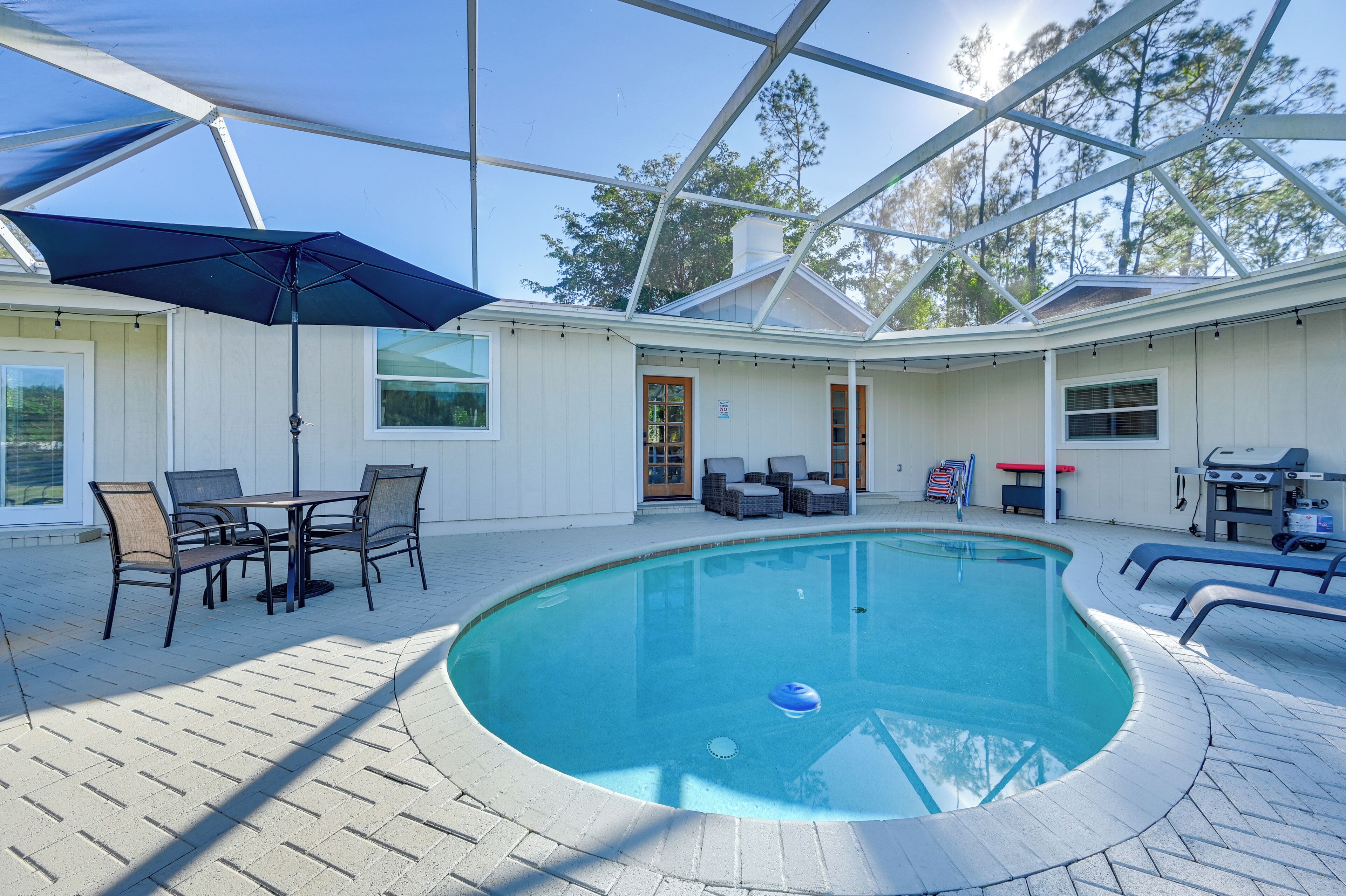 Un espace piscine doté d’un patio couvert, de mobilier d’extérieur et d’un barbecue.