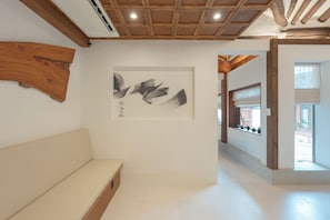 Ein Flur mit Holzboden, einer weißen Bank und einem an der Wand befestigten Kunstwerk.