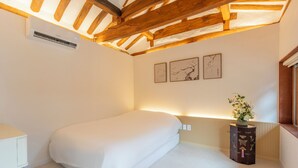Um quarto com uma cama de solteiro, uma mesa de cabeceira, um radiador e uma obra de arte na parede.