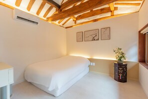 Ein Schlafzimmer mit einem Einzelbett, einem Nachttisch, einer Heizung und Wandbildern.